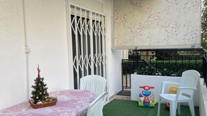 Ein Balkon mit Esstisch, Stühlen, einem kleinen Weihnachtsbaum und Kinderspielzeug.