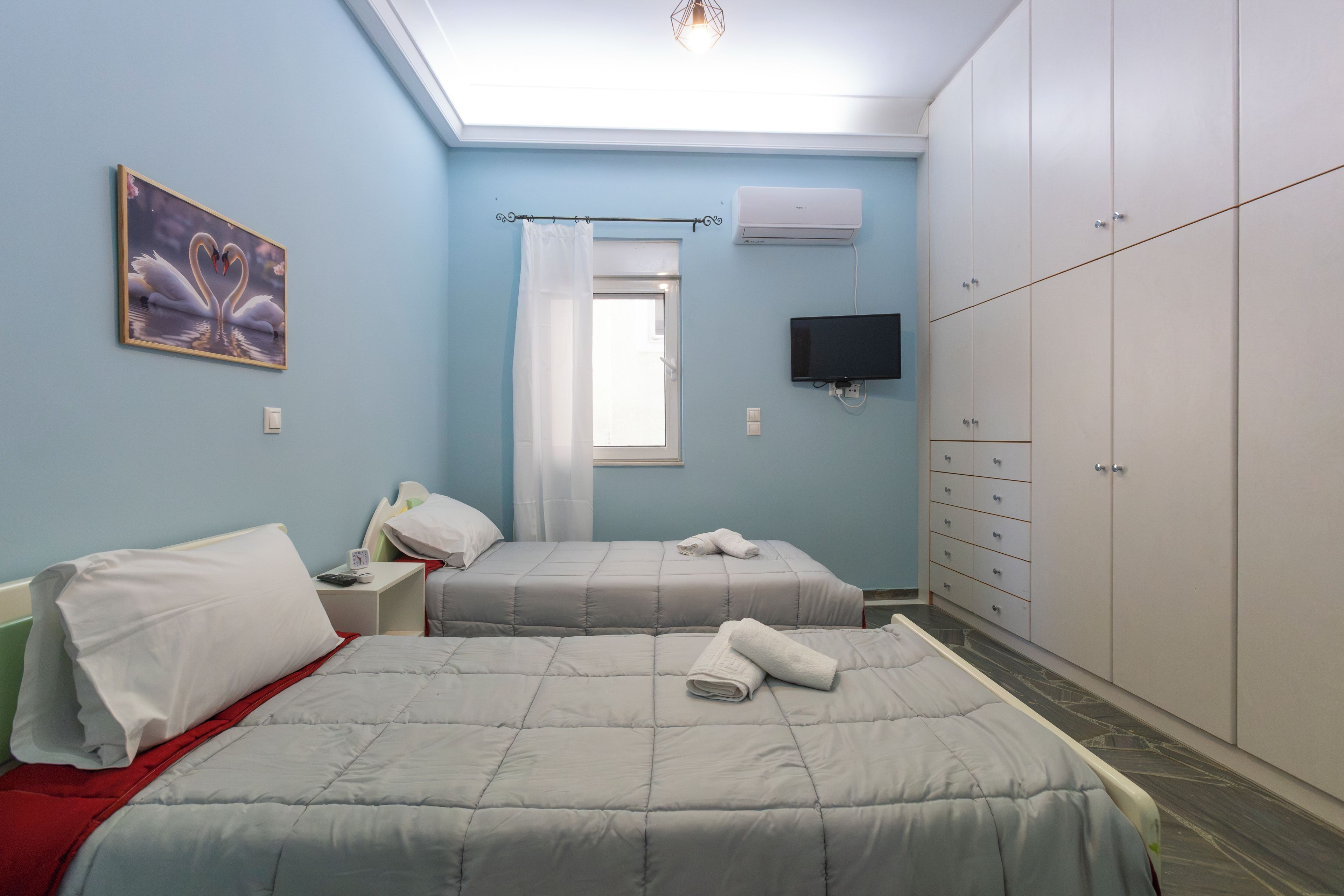 Ein Schlafzimmer mit zwei Betten, einem Fernseher, einem Kleiderschrank und einem Bild an der Wand.