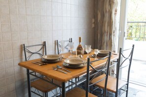 A dining table set for six with metal chairs, plates, cutlery, and wine glasses. - Marias Cozy getaway in Glyfada (Glifada)