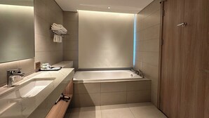 Une salle de bain moderne avec une grande baignoire, un meuble-lavabo avec un miroir et un placard en bois.