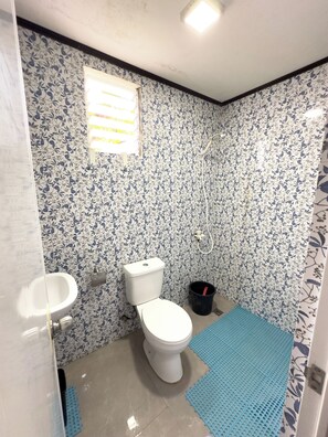 Een badkamer met toilet, bidet en een blauwe mat op de vloer.