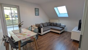 Un amplio espacio de sala con una mesa de comedor, un sofá y un tragaluz.