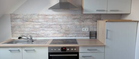 Een moderne keuken met een houten spatwand, roestvrijstalen apparatuur en witte kasten.