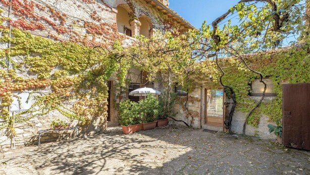 Ein Innenhof mit Steinboden, einer Holztür und einem weißen Sonnenschirm.