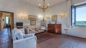 Een ruime woonkamer met een open haard, een kroonluchter en een groot raam met een prachtig uitzicht.