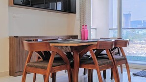 Un comedor con mesa y sillas de madera, un armario empotrado y un ventanal con vistas a edificios.