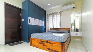 Un dormitorio con una cama de madera, un armario azul oscuro, un ventilador de techo y un baño con espejo.