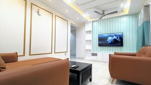 Una sala de estar moderna con dos sofás marrones, una mesa de centro negra y un televisor montado en una pared azul claro.