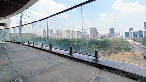 Un pasillo con barandilla de vidrio que da a una vista panorámica de la ciudad, con rascacielos y obras en construcción.