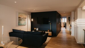 A modern living room with a dark-colored sofa, a glass coffee table, and a painting on the wall. - Romantic gîte, chic love room: L'alcôve Clisson in the heart of the medieval town (Clisson)