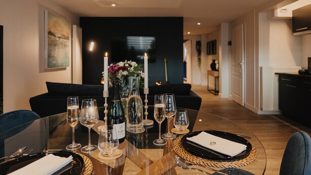 A dining table set for a meal with wine glasses, a bottle of wine, and a candle centerpiece. - Romantic gîte, chic love room: L'alcôve Clisson in the heart of the medieval town (Clisson)