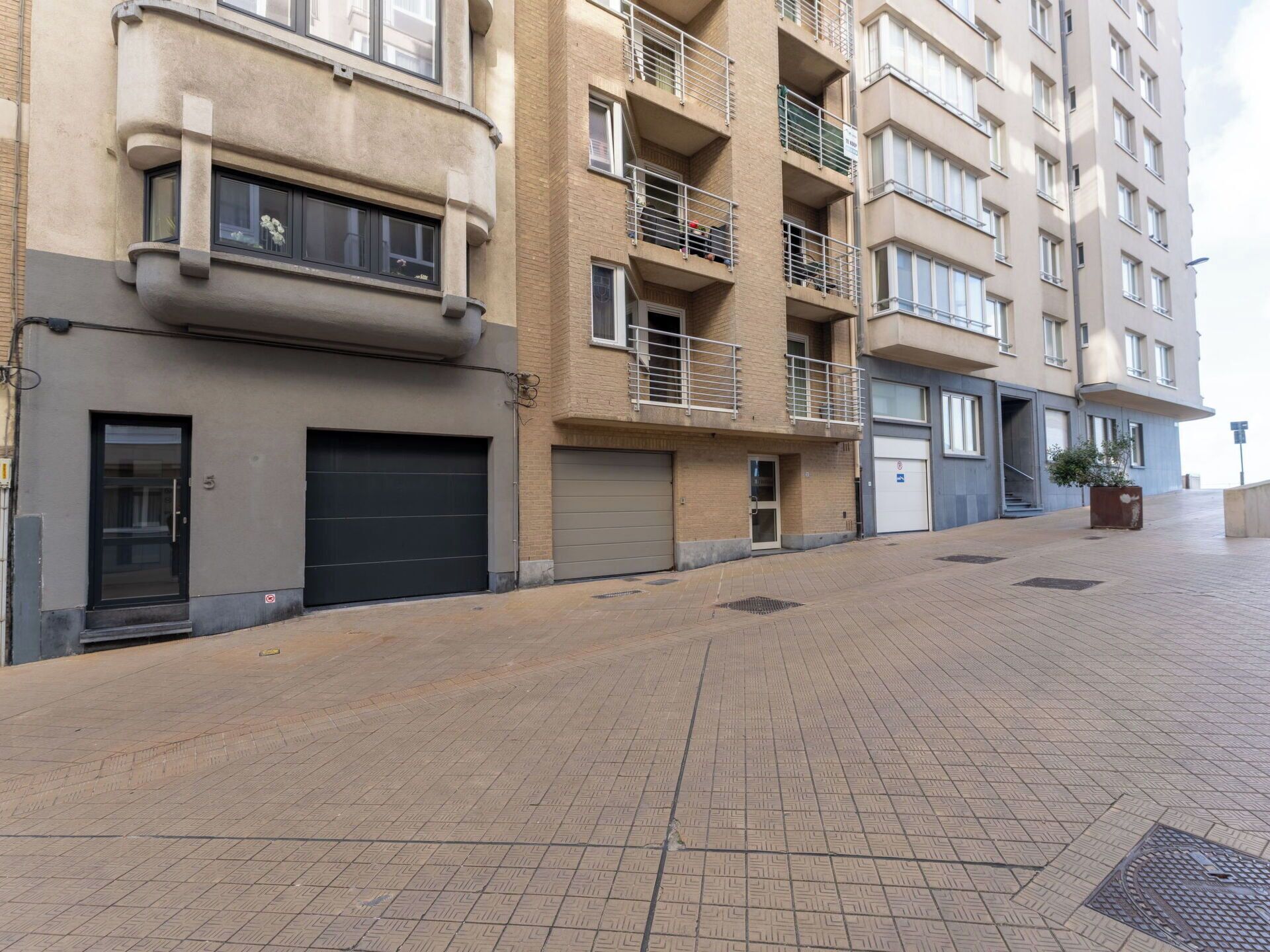 Ein mehrstöckiges Wohngebäude mit flacher Fassade, Balkonen und einem gepflasterten Gehweg.