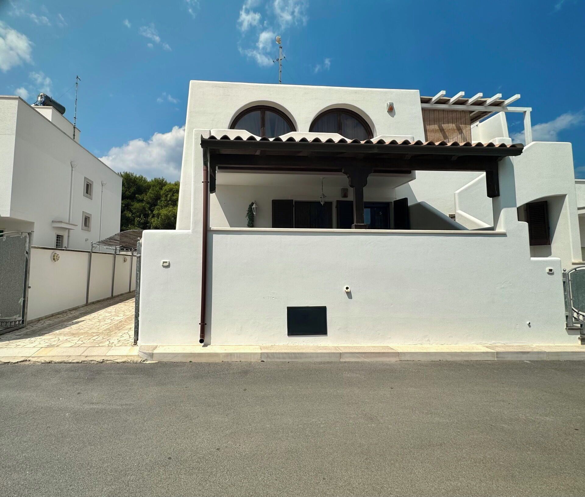 Un edificio moderno con tetto piatto, due ampie finestre ad arco e una zona esterna coperta.