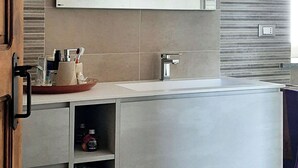 Uma cozinha moderna com uma bancada branca ampla, uma pia embutida e um espelho fixado na parede.