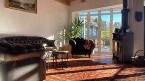 Un salón acogedor con sofá de cuero, alfombra estampada, una mesita y una chimenea.