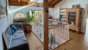 Un loft espacioso con techo de madera, un ventanal grande, sofá, mesa de comedor y área de cocina.