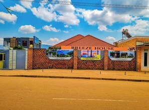 A building named 'Breeze House' with a red roof and brick facade. There are two signs on the front with images of spa services. - Breeze House Gikondo (Kigali)