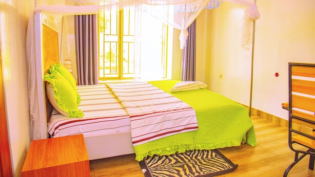 A room with a bed, a bench, and a zebra-patterned rug. - Breeze House Gikondo (Kigali)