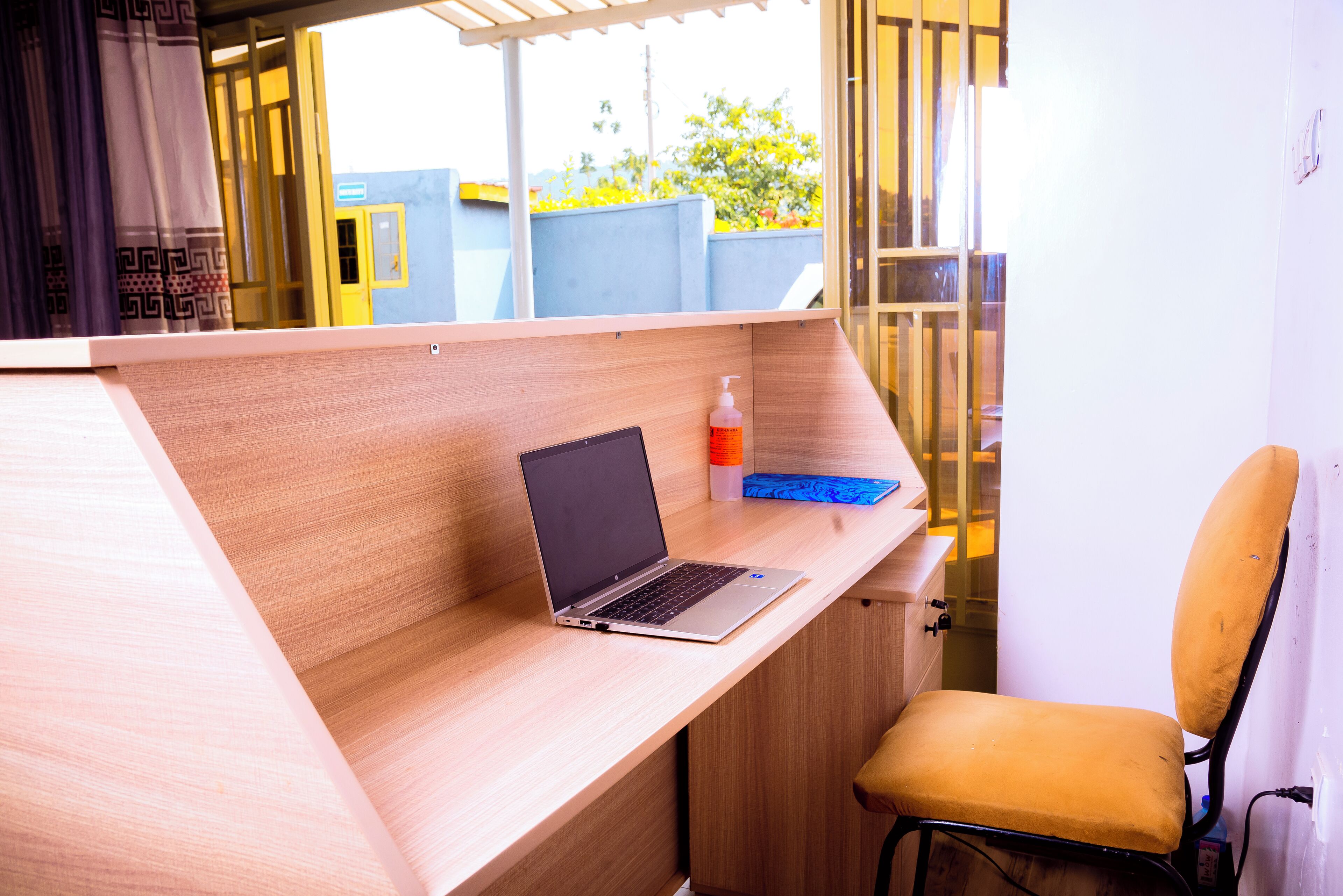 Un espacio de trabajo moderno con una computadora portátil sobre un escritorio de madera, una silla y un frasco de gel antibacterial.