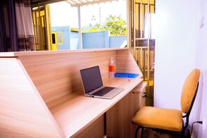 A modern workspace with a laptop on a wooden desk, a chair, and a bottle of hand sanitizer. - Breeze House Gikondo (Kigali)