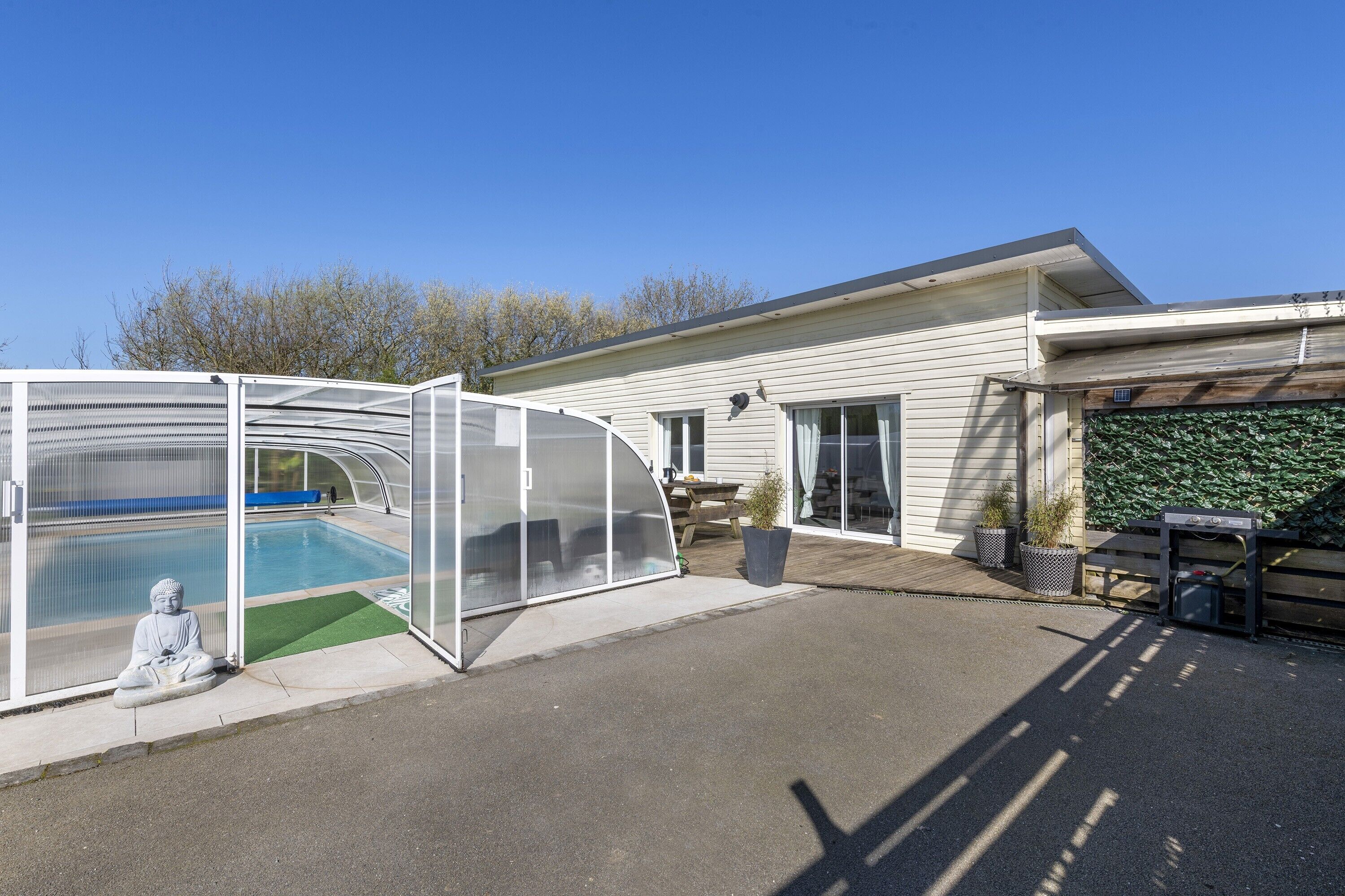 Une maison avec une piscine, un patio couvert et une statue.