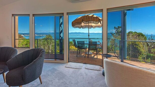 Un balcon spacieux offrant une vue sur la mer, aménagé avec deux fauteuils et une table.