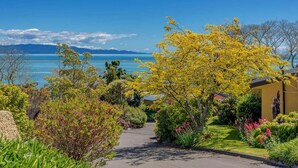 Un quartier résidentiel avec un sentier menant à une maison offrant une vue sur la mer et les montagnes.