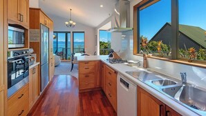 Une cuisine moderne avec des meubles en bois, des appareils en acier inoxydable et une grande fenêtre donnant sur un paysage magnifique.
