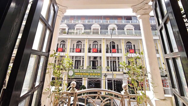Un immeuble doté de nombreuses fenêtres et de balcons, sur lequel on peut voir une enseigne avec du texte en vietnamien.