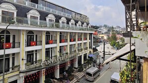 Un hôtel avec une enseigne bien visible, de nombreux balcons et une vue sur la rue, où l’on peut voir des piétons et des véhicules.