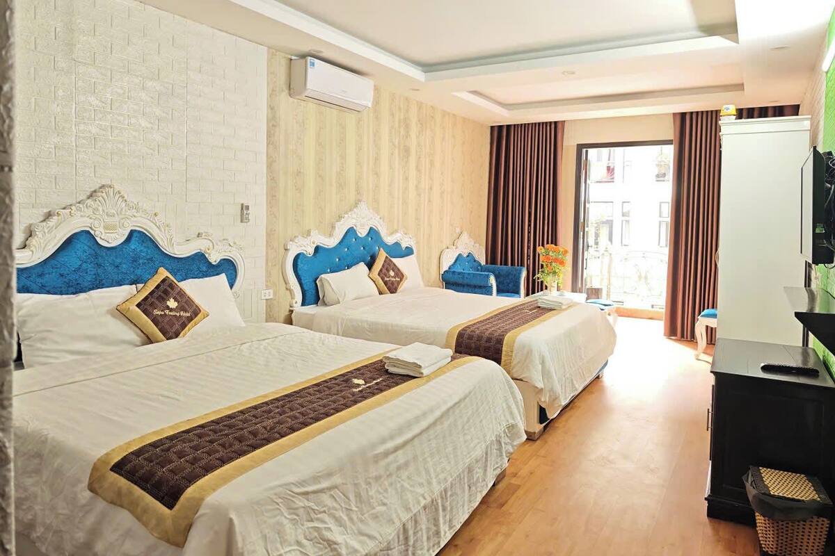Habitación de hotel con dos camas, un televisor y una ventana con cortinas.