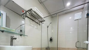 A modern bathroom with a white sink, toilet, and glass shower enclosure. - The Sóng - Ruby Star Hotel Apartment (Ho Chi Minh City)