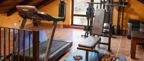 An attic gym with a treadmill, bench, kettlebells, and a pull-up bar.