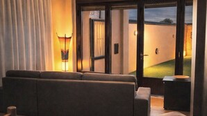 A living room with a sofa, a lamp, and a view of a golf course through a glass door. - Chalet in Rivero de Posadas with Pool (Rivero de Posadas)