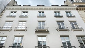 En byggnad med flera våningar och en symmetrisk fasad, med jämnt fördelade fönster och balkonger med metallräcken.