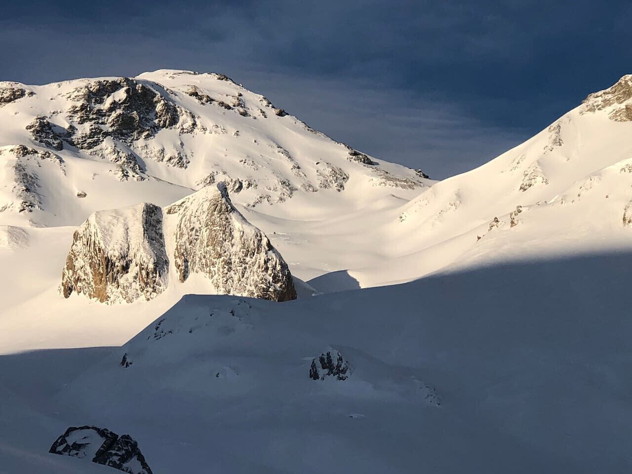 A snow-covered mountain landscape with rocky outcrops.