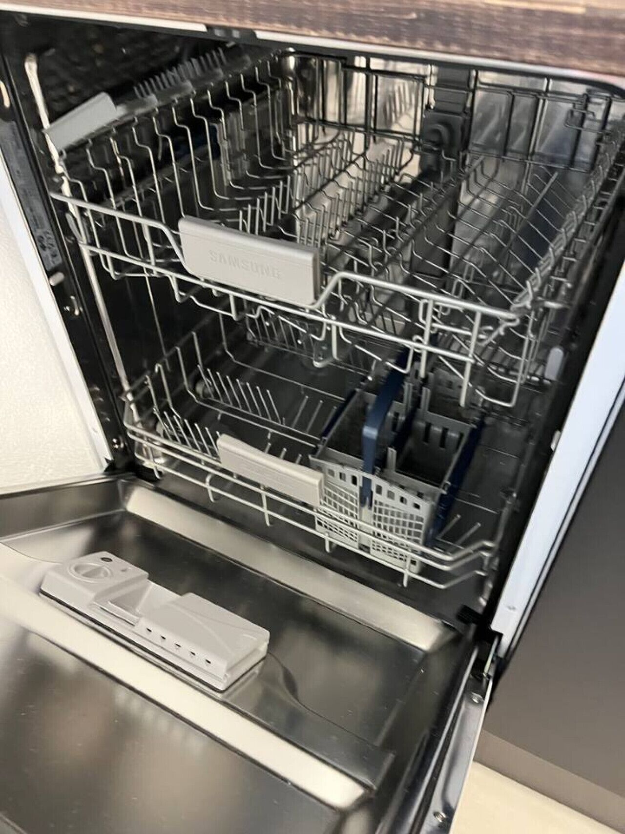 Un lave-vaisselle ouvert, doté de plusieurs niveaux et d’un panneau de commande.