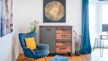 Ein stilvolles Wohnzimmer mit blauem Sessel, Holzschrank und großem abstrakten Gemälde.