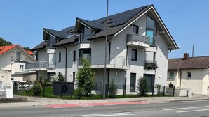 A modern multi-story residential building with balconies, a flat roof, and a visible streetlight. - 90m2 Loft I Kaffee I Terrasse I E-Parkplatz (Rosenheim)