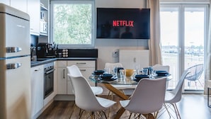 A modern kitchen with a dining area, a large window, and a flat-screen TV displaying 'NETFLIX'. - YAYstay - 58m2 I balkony I 56` Smart TV I train (Mühldorf am Inn)