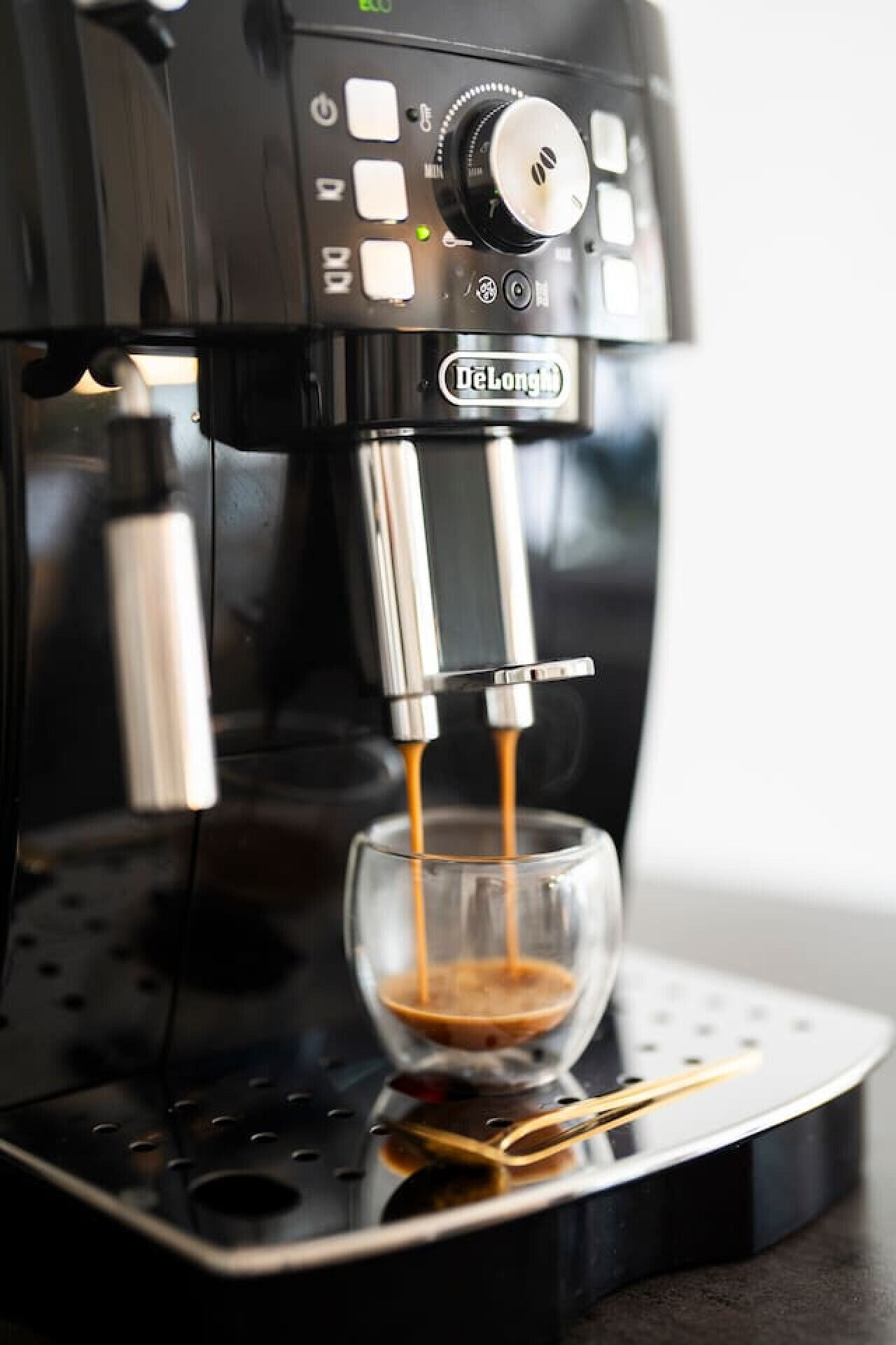 A De'Longhi espresso machine dispensing coffee into a glass.