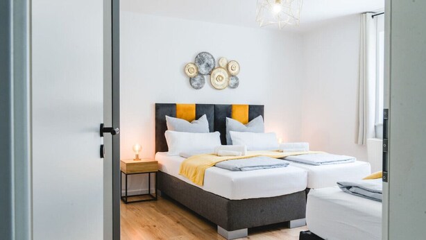 Un dormitorio moderno con cama doble, mesitas de noche y un adorno en la pared.