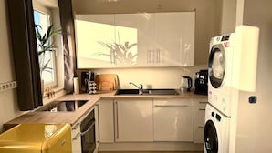 Cocina compacta con un lavamanos, lavadora y un electrodoméstico amarillo.