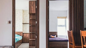 A room with a bed, a wooden wardrobe, a small table, and a chair.