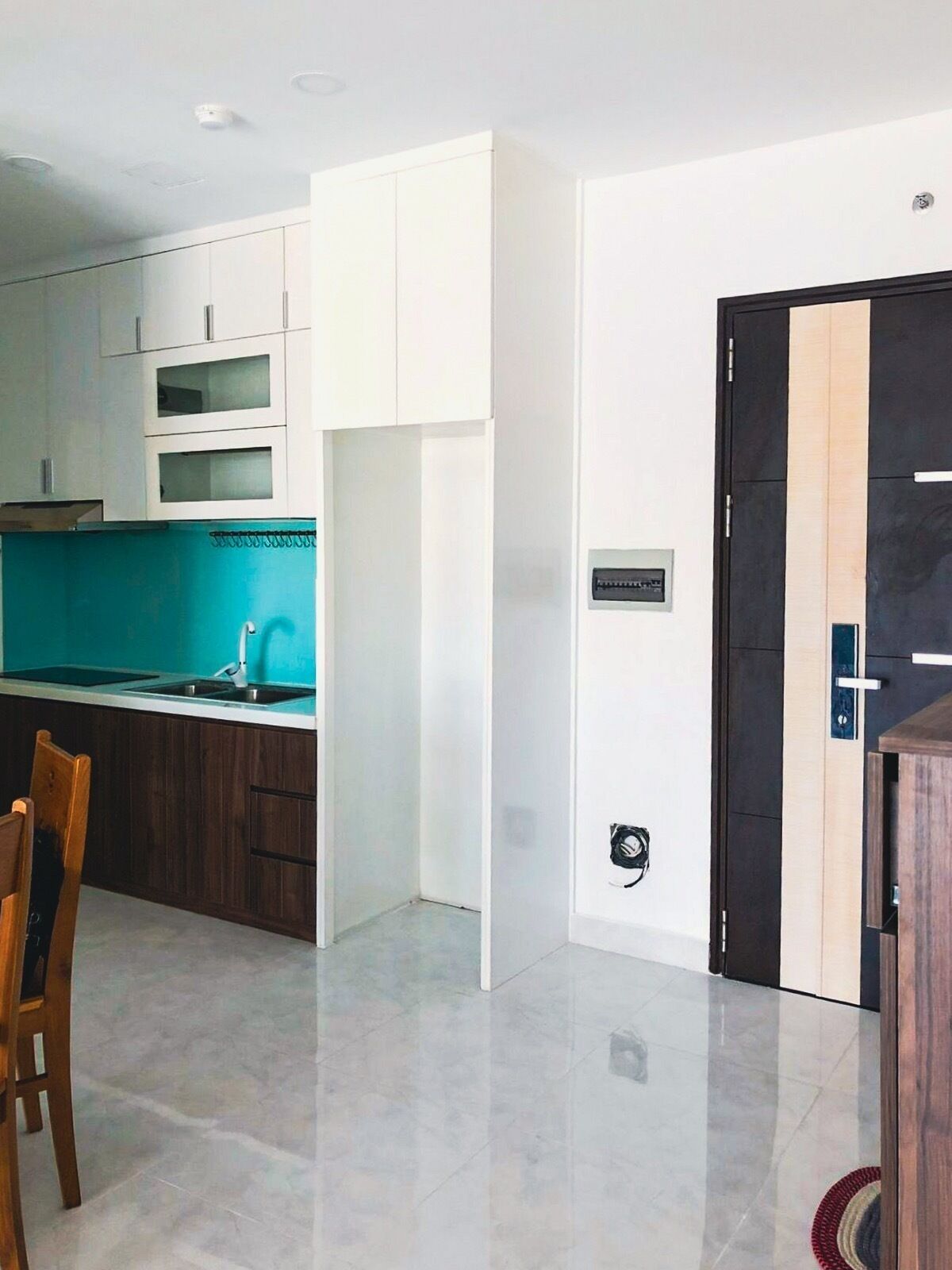 A modern kitchen with white cabinets, a teal backsplash, and a black door.