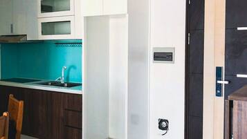 A modern kitchen with white cabinets, a teal backsplash, and a black door.