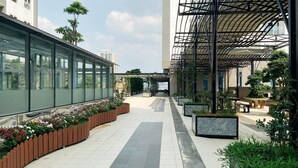 A modern building with a covered walkway, potted plants, and a tiled floor.