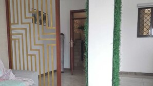 A hotel lobby with a grey sofa, a decorative yellow and white partition, a green plant, and a tiled floor. - Hoyjiifka Hotel Azora (Moyale)