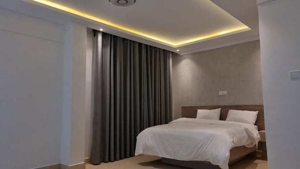 A modern hotel room with a large bed, a ceiling light fixture, and a curtain. - Hoyjiifka Hotel Azora (Moyale)
