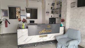 A hotel reception area with a marble counter, a reception desk, a blue armchair, and a fire extinguisher. - Hoyjiifka Hotel Azora (Moyale)